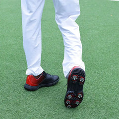 Man wearing Sampson Men's Golf Shoes with red and black design on green grass fairway, showcasing grip and style.