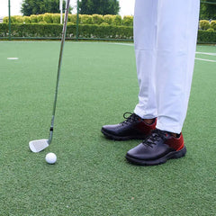 Golf player wearing Sampson Men's Golf Shoes preparing to putt on a green course.